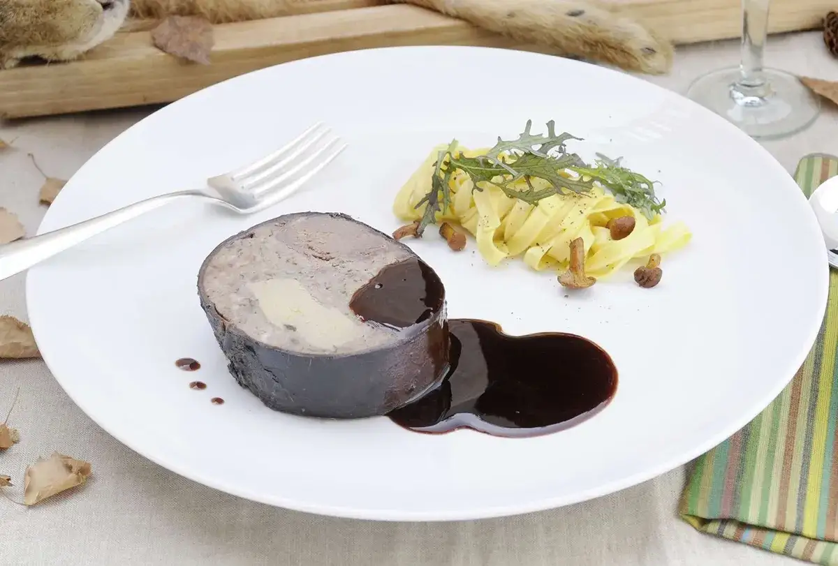 Un généreux morceau de lièvre à la royale, nappé de sauce, accompagné de pâtes fraîches et de champignons.