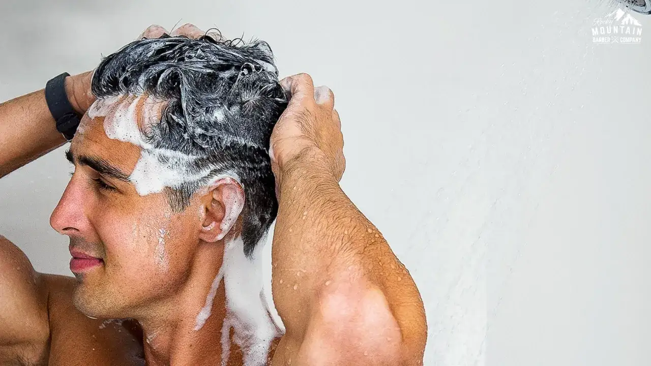 Hombre con pelo graso se lava el cabello con champ&uacute; en la ducha.