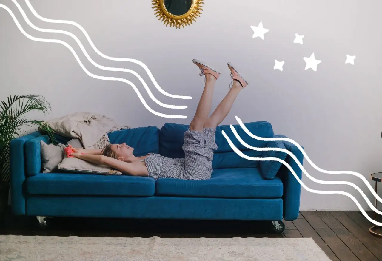 Frau liegt entspannt auf einem blauen Sofa, Beine hoch, genie&szlig;t den entspannten Feierabend. Wei&szlig;e Wellen und Sterne schm&uuml;cken die Wand.
