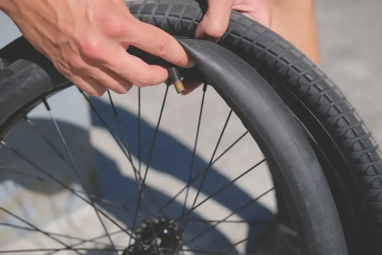 Handen vervangen een lekke band van een racefiets. De nieuwe binnenband wordt naast de oude gelegd.