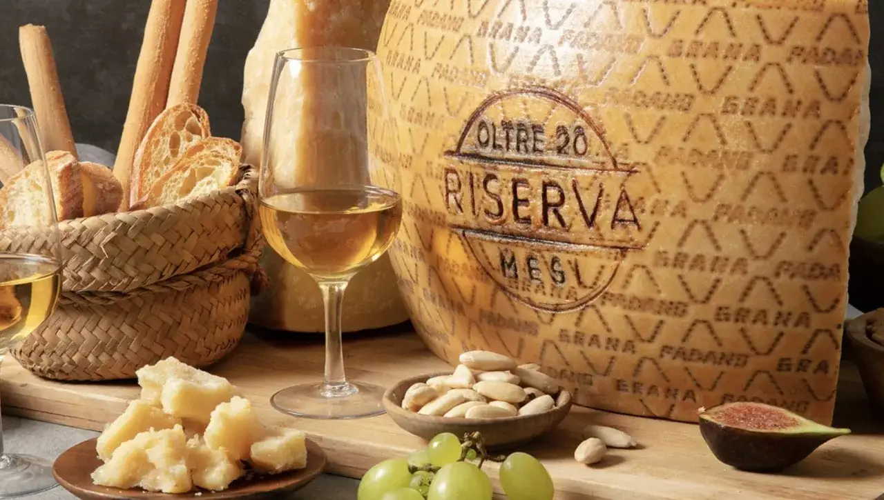 Un bicchiere di vino bianco accompagna un pezzo di Grana Padano Riserva, pane e frutta secca.