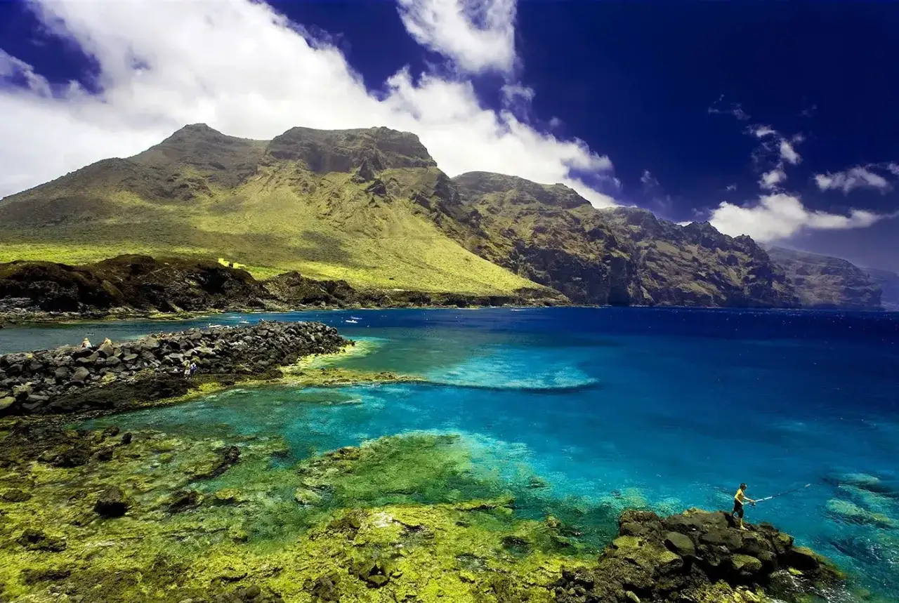 Un pescatore ammira la vista mozzafiato, forse sull'isola più bella delle Canarie. Acque cristalline, scogliere imponenti e un cielo azzurro intenso.