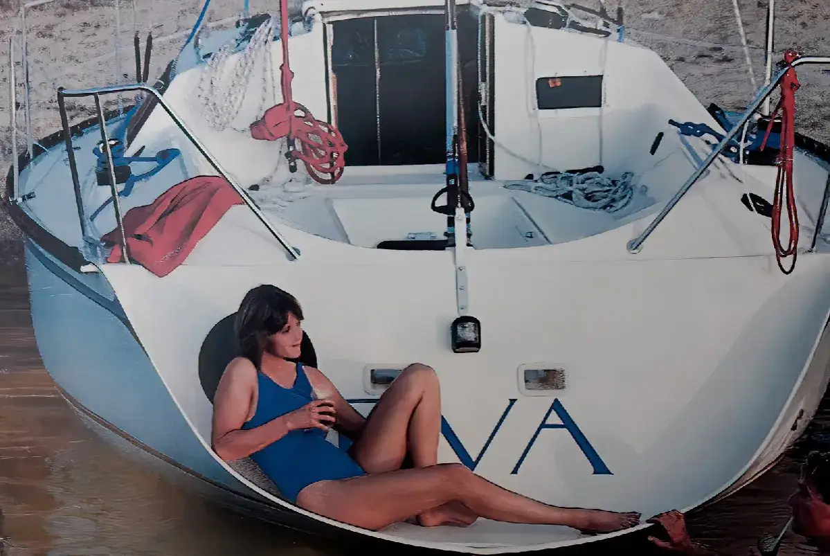 Une femme en maillot de bain bleu se détend sur le pont d'un voilier Kelt 850.