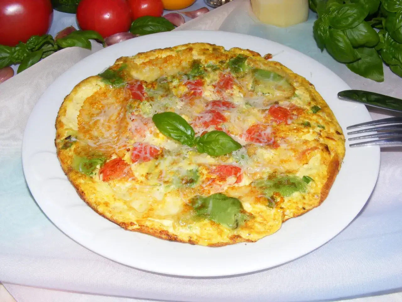 Pyszny omlet z awokado, pomidorami i serem, udekorowany listkiem bazylii. Idealny na śniadanie.