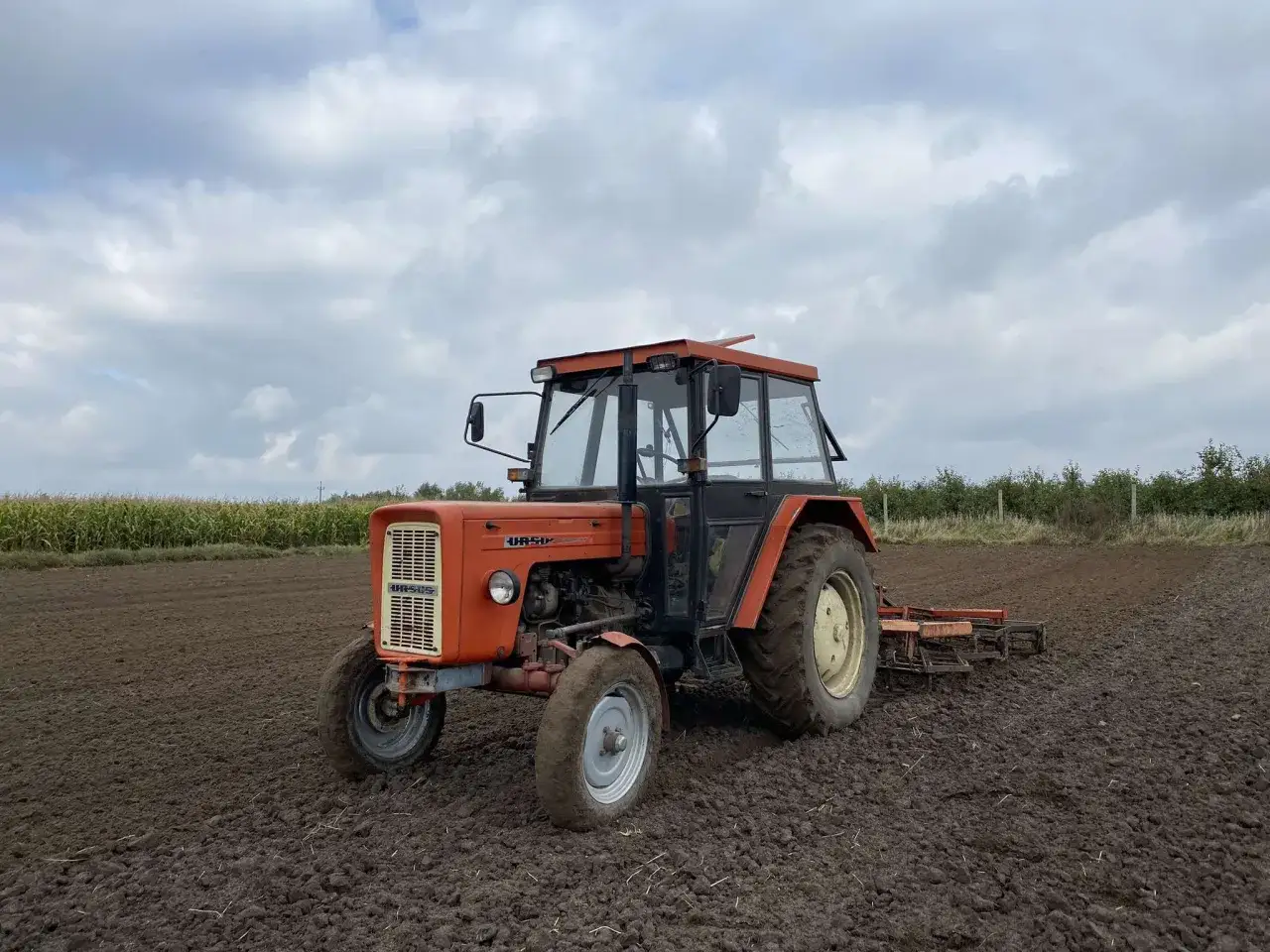 Pomarańczowy Ursus C-360 na polu, gotowy do pracy. Warto pamiętać, ile oleju do silnika C-360 potrzebuje, by pracował bez zarzutu.