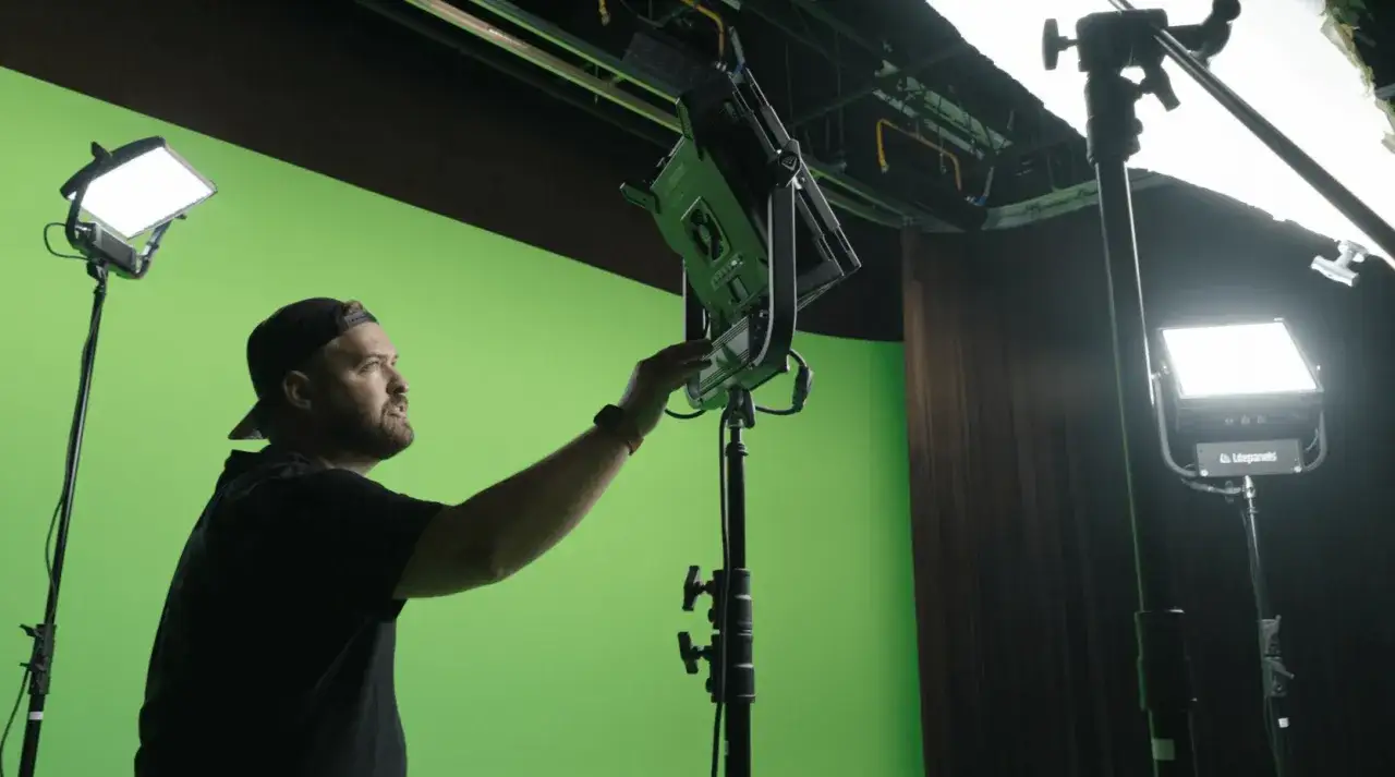 Tecnico regola luci in uno studio con green screen cinema.