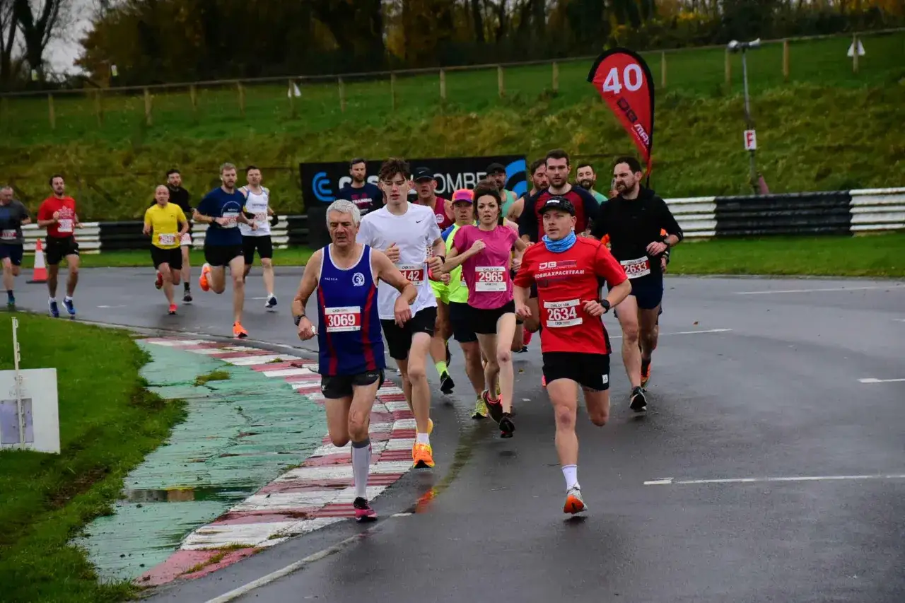 Grupa biegaczy na trasie, niektórzy w kolorowych koszulkach. Czas na 3 km!