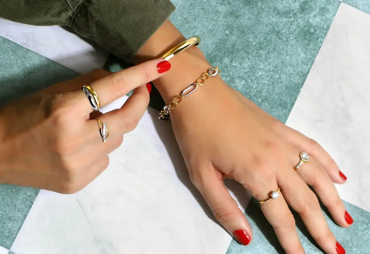 Manos adornadas con anillos y pulseras de oro o plata.