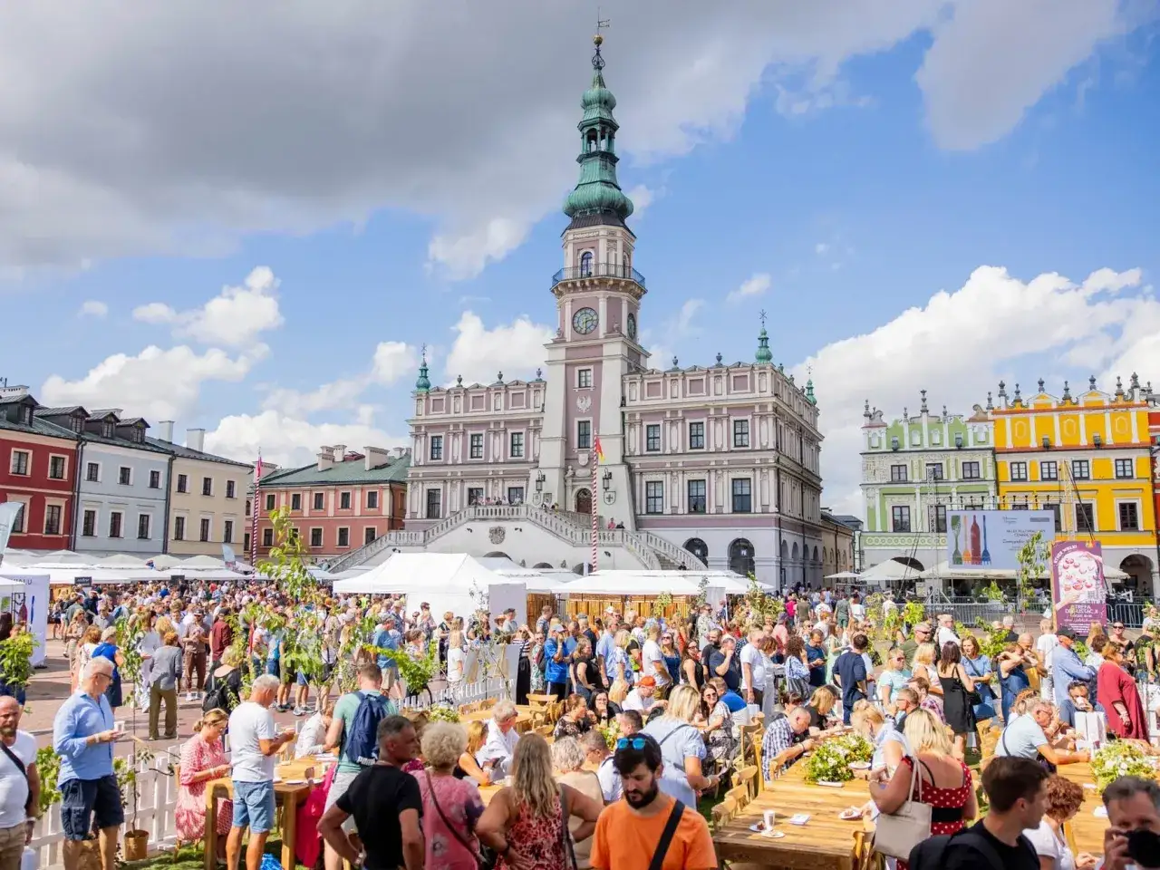 Tłumy ludzi na Rynku Wielkim w Zamościu podczas festiwalu wina. W tle zabytkowa kamienica ormiańska i ratusz.