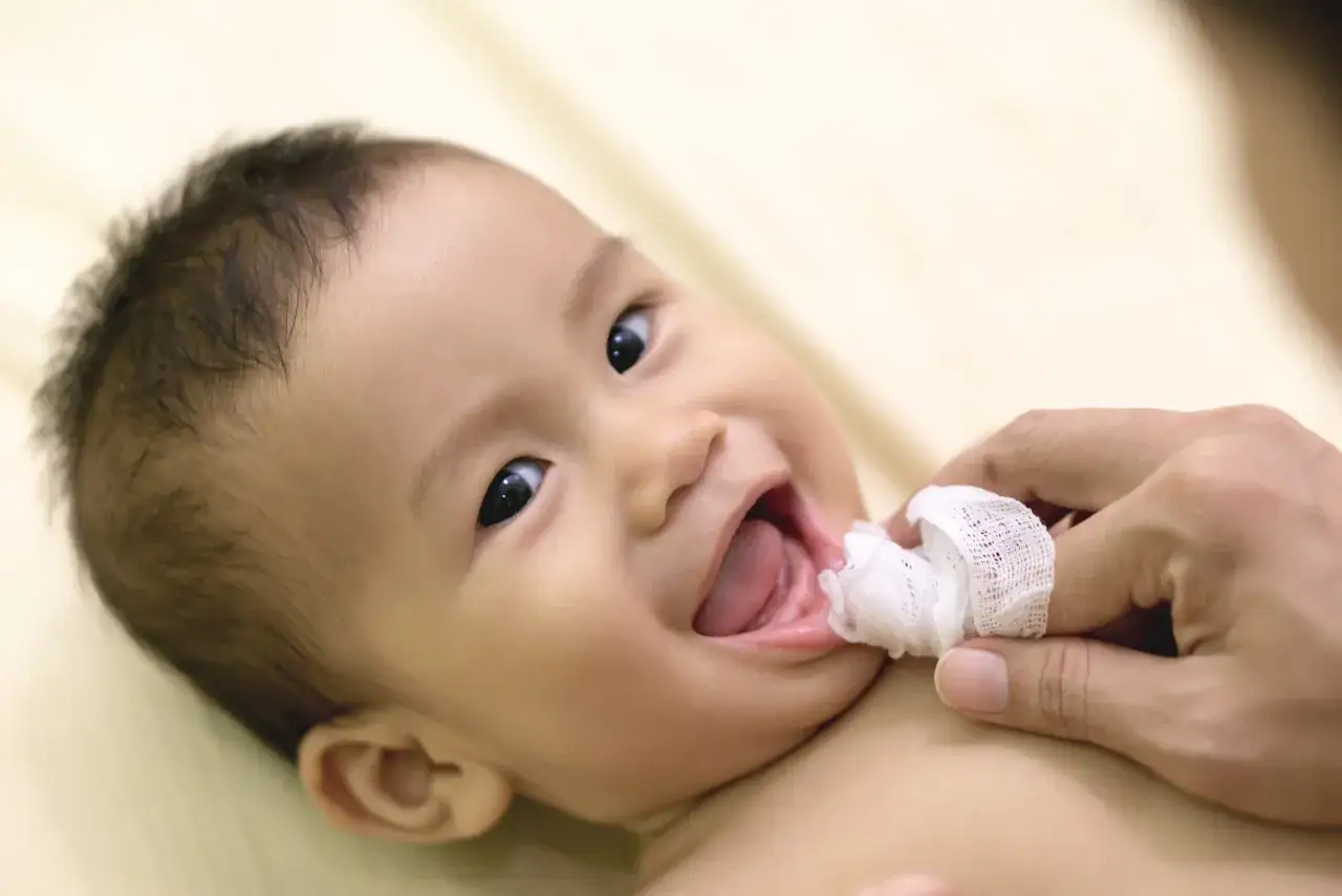 Un sorriso contagioso mentre si pratica l'igiene orale neonato con una garza.