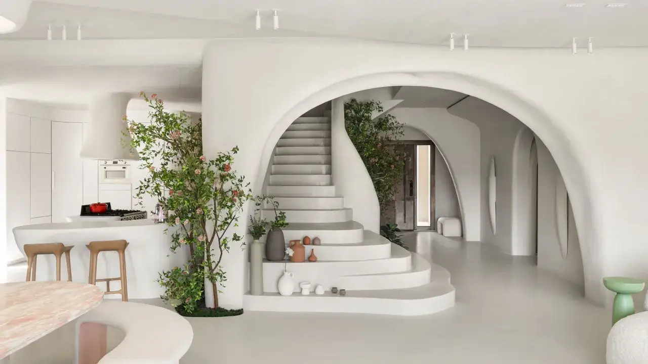Un hogar de estilo japandi con escaleras orgánicas, una cocina minimalista y un árbol frondoso.