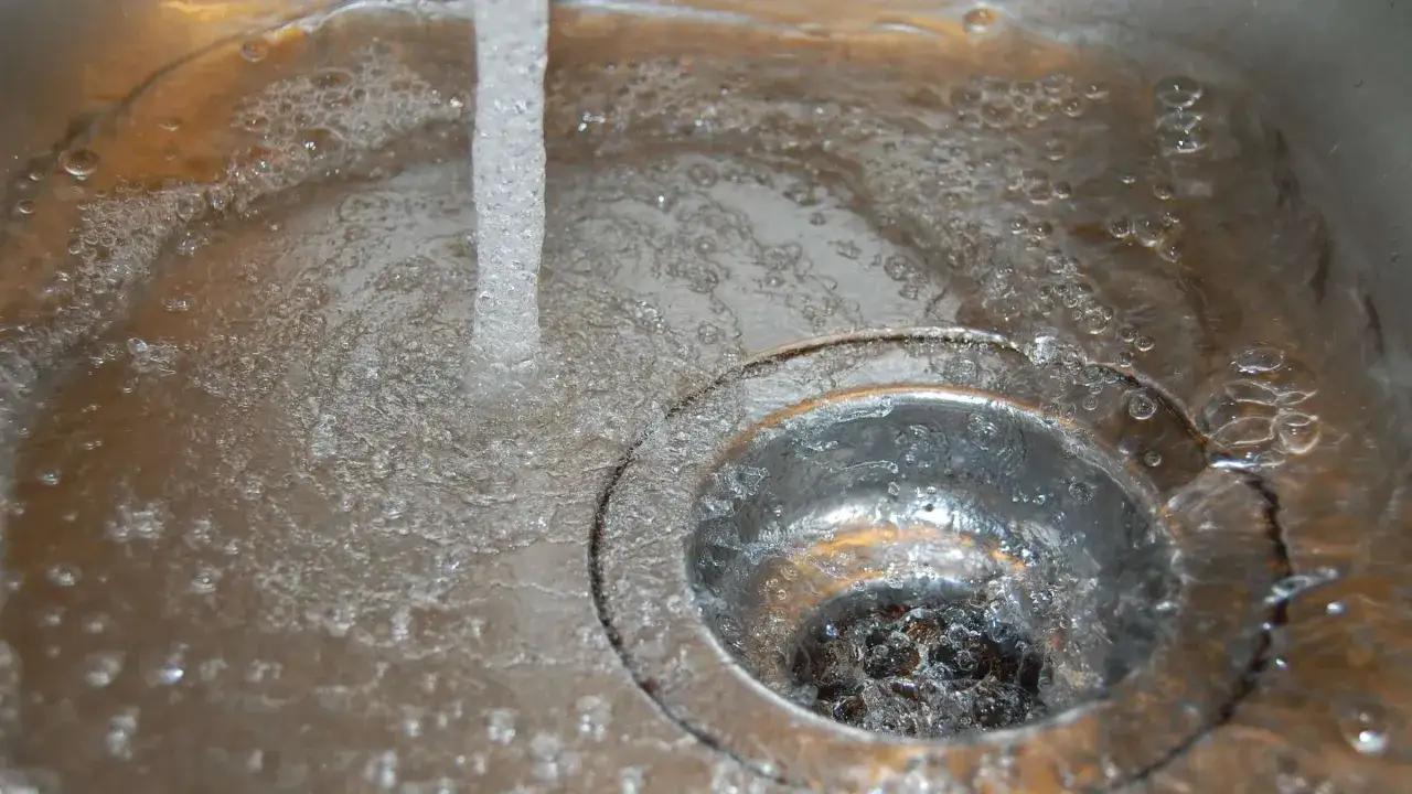 Wasser fließt in eine Spüle, die möglicherweise einen undichten Duschabfluss reparieren muss.
