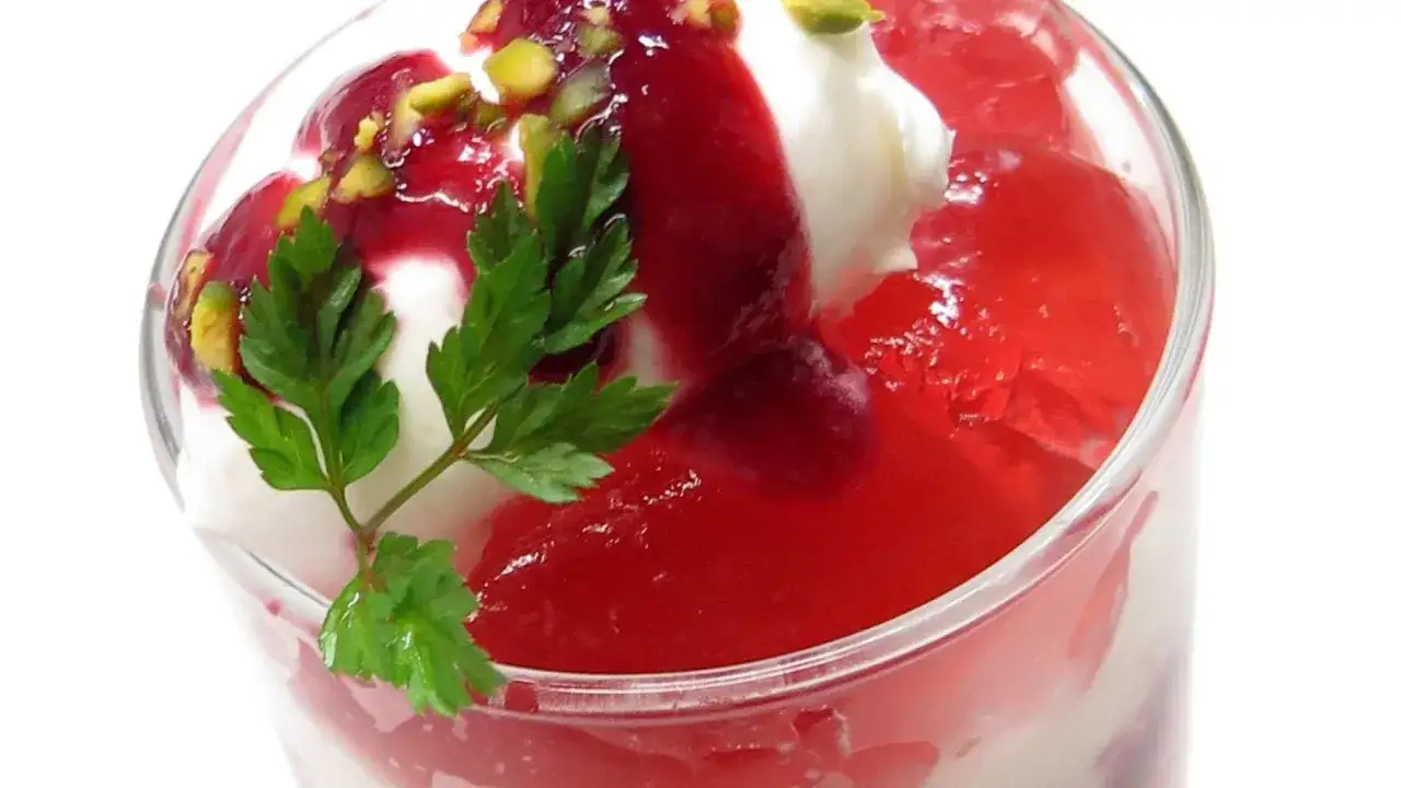 Delicioso postre con helado, gelatina roja y pistachos, perfecto para disfrutar de los dulces de verano.