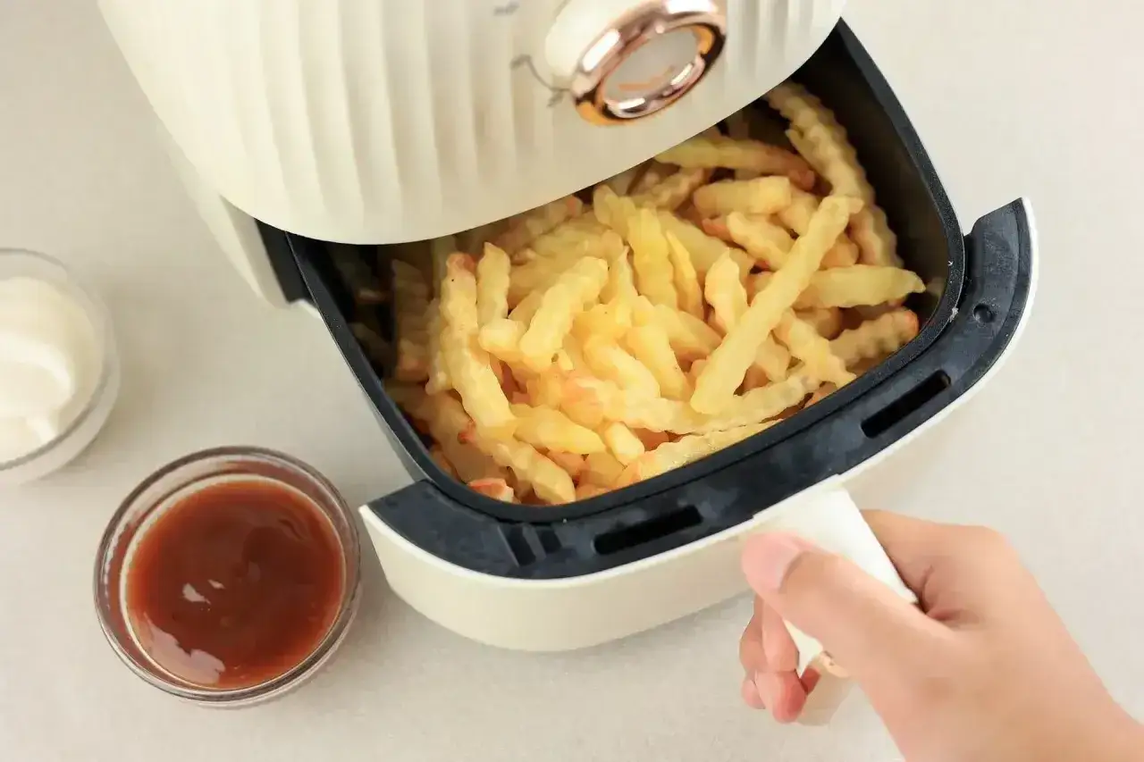 Chrupiące frytki w airfryerze, gotowe do podania z keczupem i majonezem. Idealna przekąska, gdy zastanawiasz się, ile piec frytki w airfryer.