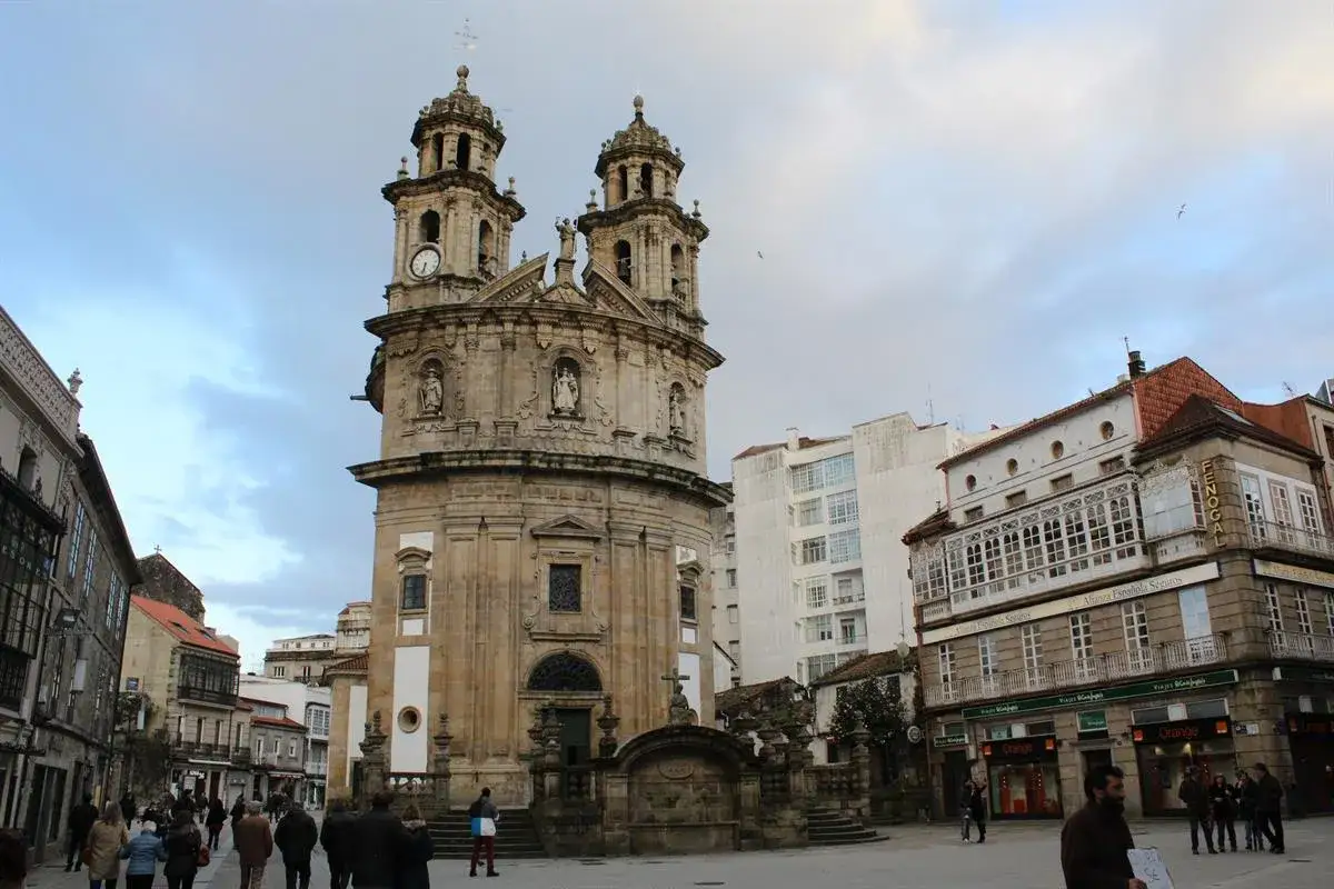 Plaza de la Peregrina en Pontevedra, un lugar ideal que ver. Fachada barroca de la iglesia, edificios históricos y gente paseando.
