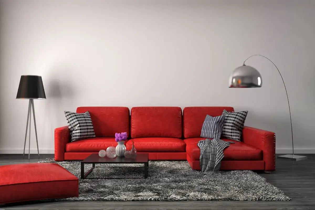 Un canapé rouge vif, des coussins à motifs, un tapis gris moelleux et des lampes modernes. Quelle couleur associer avec un canapé rouge ? Le gris et le noir sont des choix sûrs.