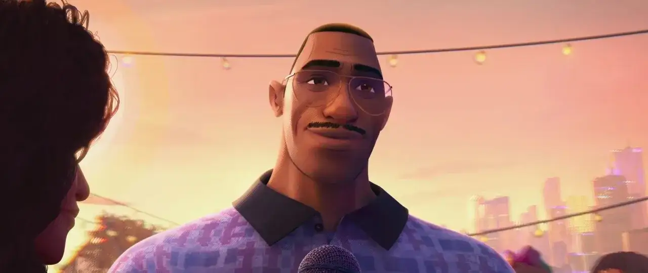 Le père de Miles Morales, Jefferson Davis, porte des lunettes et un micro, souriant lors d'un événement en plein air.