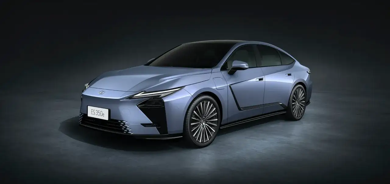 Nowy Lexus ES 350e w kolorze błękitnym, z eleganckimi felgami i nowoczesnym designem, prezentuje się na ciemnym tle.