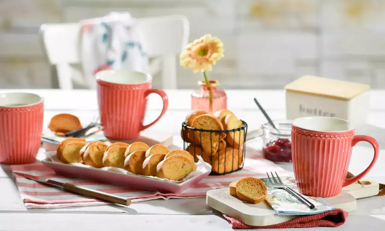 Ein liebevoll gedeckter Tisch mit Zwieback, Marmelade, Butter und Kaffee. Perfekt f&uuml;r ein gem&uuml;tliches Fr&uuml;hst&uuml;ck.