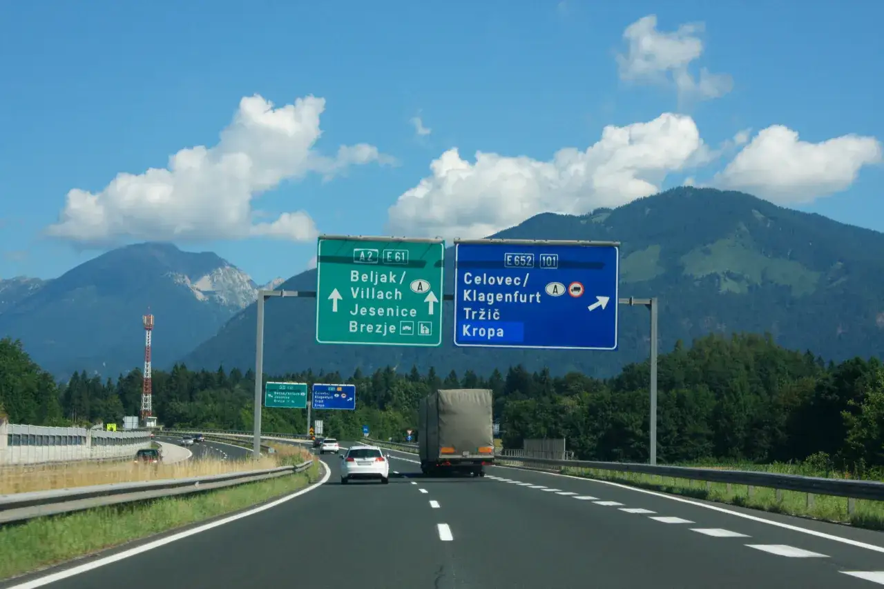 Droga w Słowenii z tablicami kierunkowymi do Beljak/Villach, Jesenice, Brezje, Celovec/Klagenfurt, Tržič i Kropa.