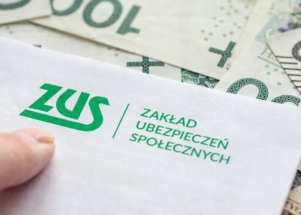 ZUS, czyli Zakład Ubezpieczeń Społecznych, to instytucja, która zajmuje się świadczeniami emerytalnymi i rentowymi. Na zdjęciu widać logo ZUS na tle polskich banknotów.