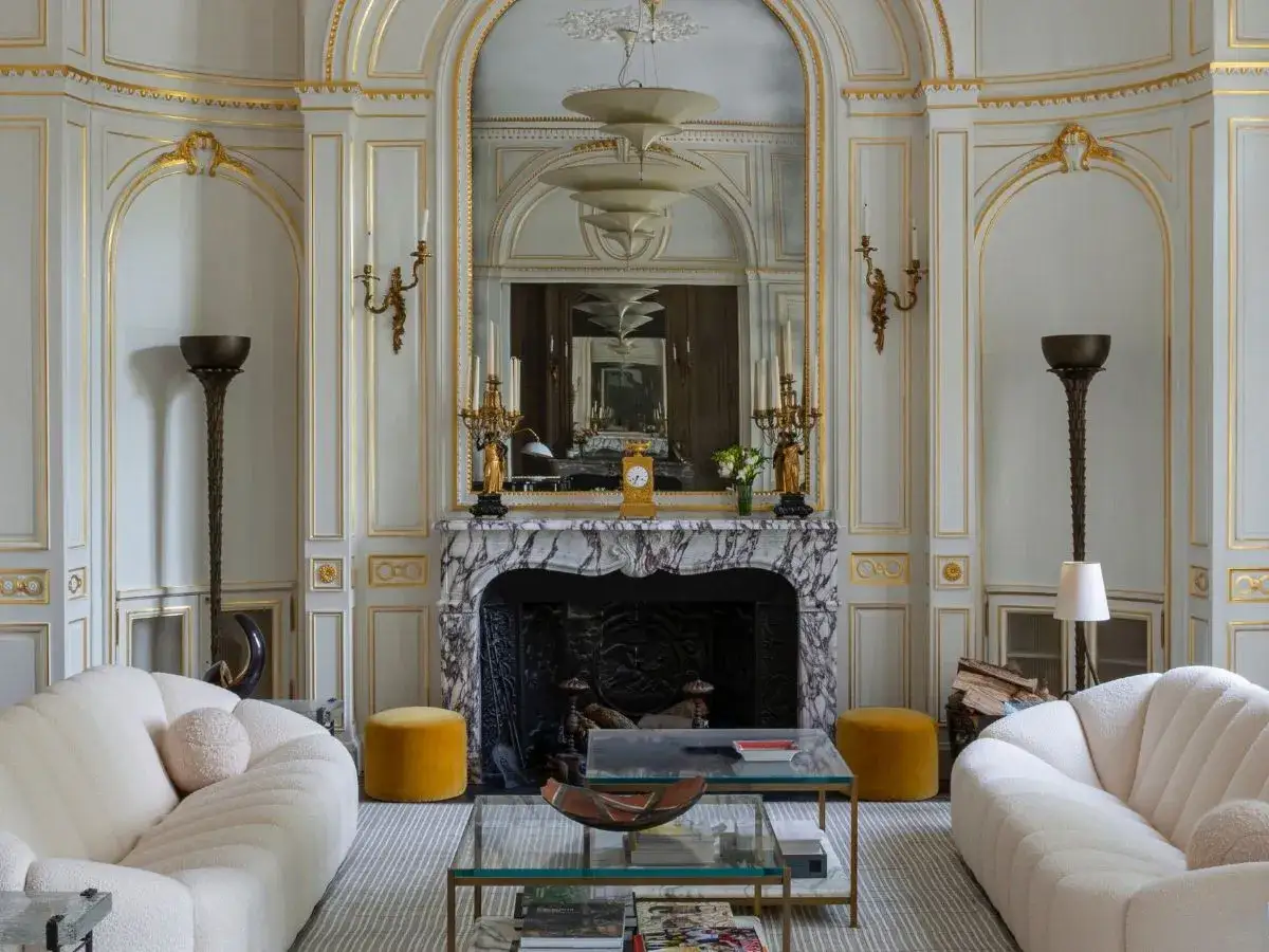 A luxurious living room with ornate gold trim, marble fireplace, and plush sofas, reminiscent of the opulent style favored by art deco artists.