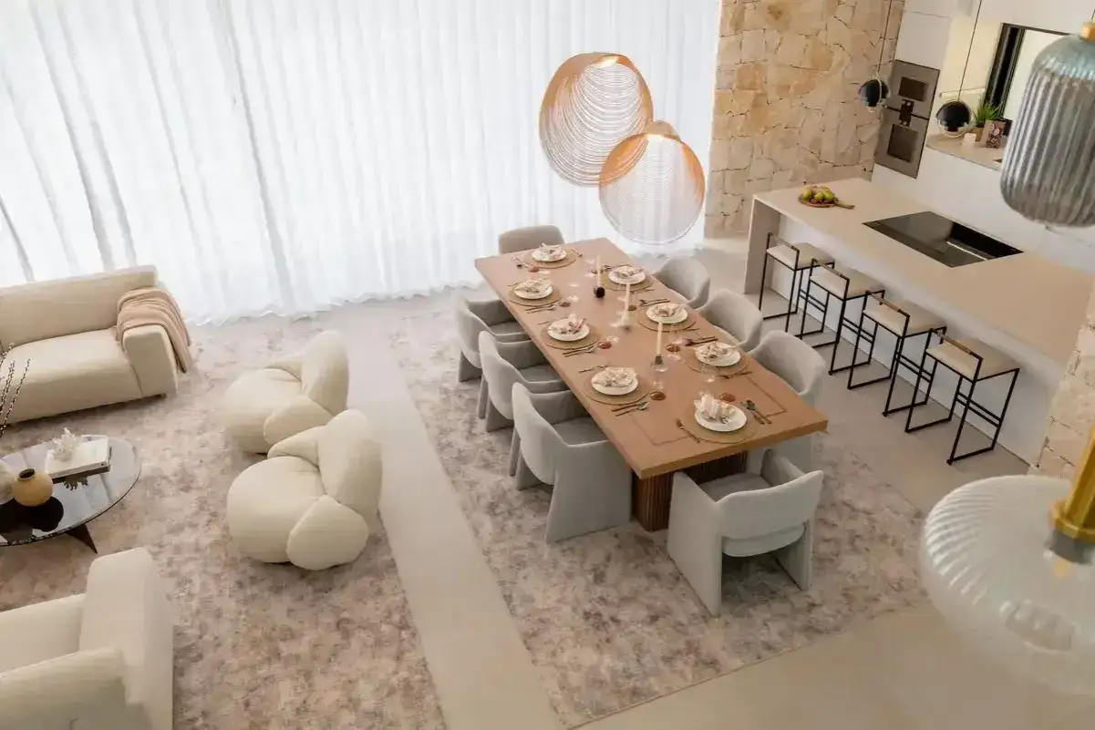 Comedor moderno con mesa de madera, sillas tapizadas y lámparas colgantes. El diseño, inspirado en el feng shui, promueve la armonía y el equilibrio.