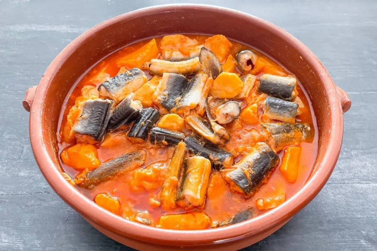 Un sabroso all i pebre, un guiso tradicional valenciano, con trozos de anguila y patatas en una salsa rojiza.