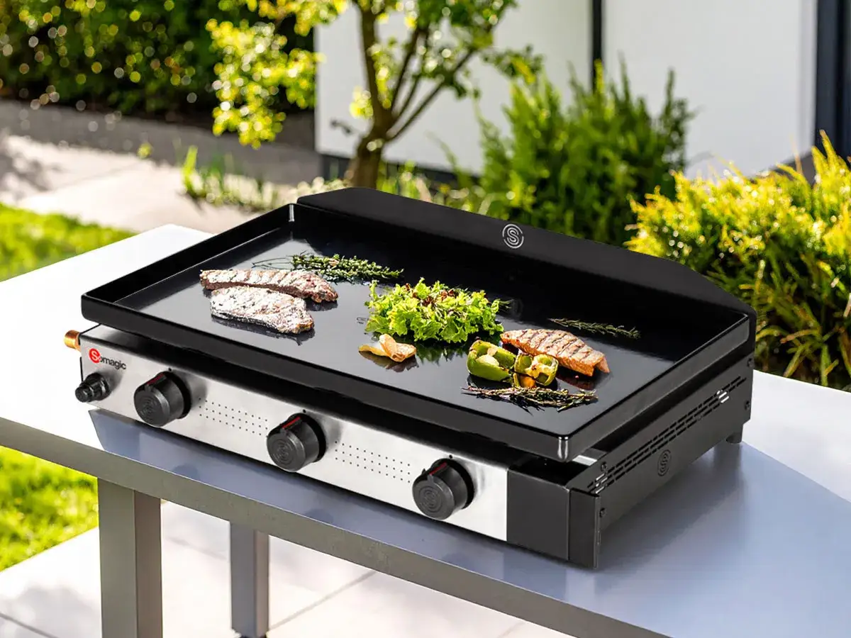 Plancha à gaz Somagic prête à l'emploi, avec des steaks et des légumes en cours de cuisson. Idéale pour allumer plancha gaz et savourer un repas en extérieur.