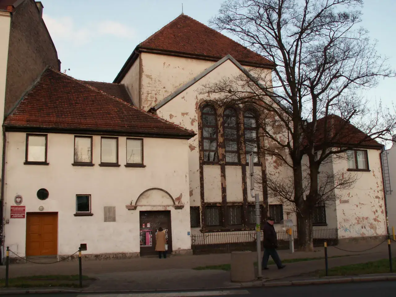 Dawna synagoga w Gdańsku, budynek z charakterystycznymi oknami i zniszczoną elewacją, stoi obok mniejszego skrzydła.