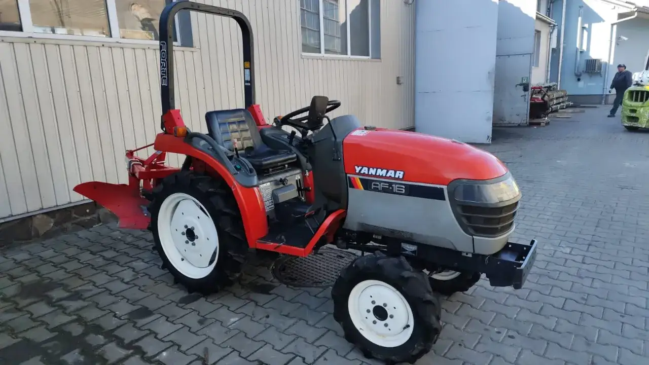 Czerwony ciągnik Yanmar AF-16 z pługiem. To jest rewers w ciągniku, który pozwala na jazdę do tyłu.