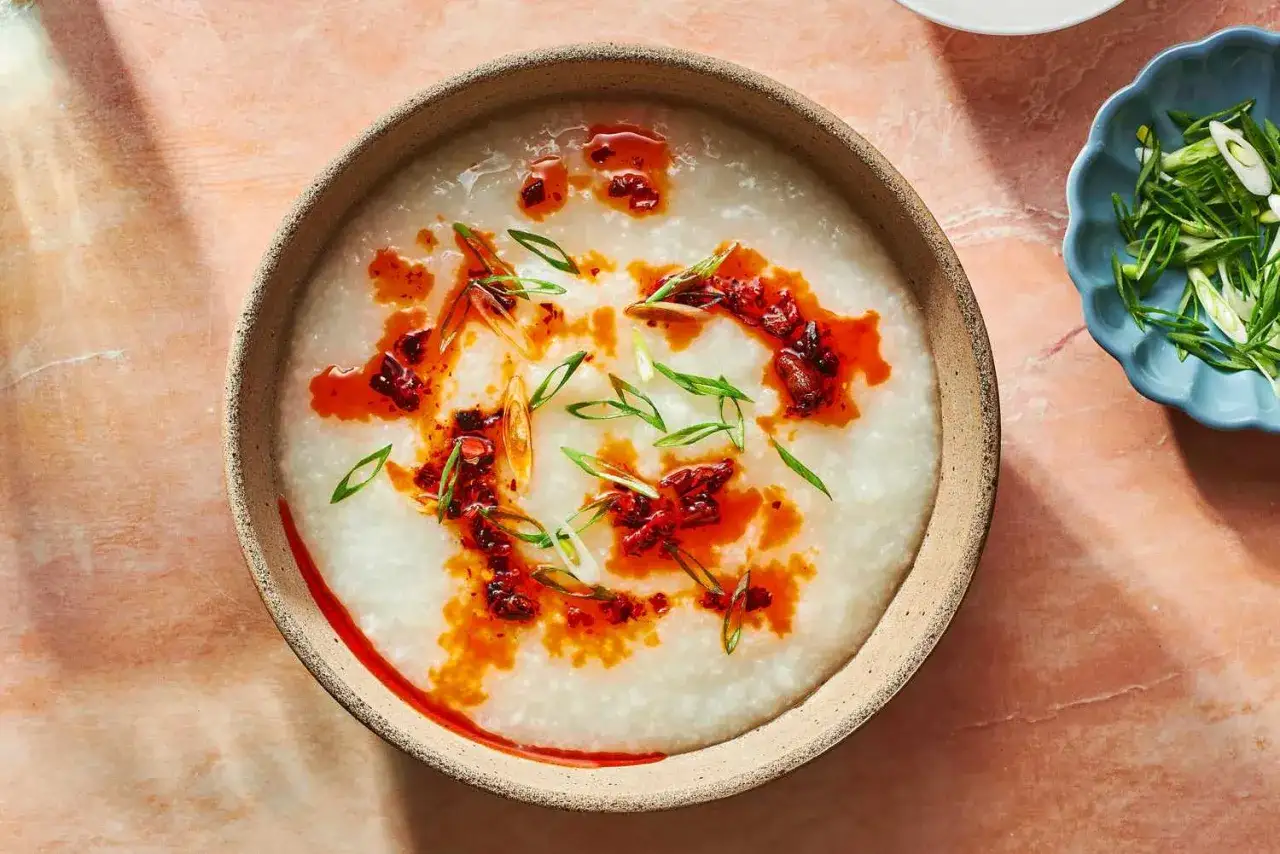 Un reconfortante plato de gachas de arroz, adornado con aceite picante y cebolleta fresca.