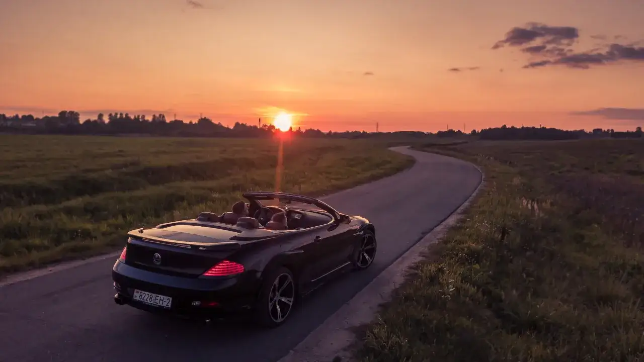 Czarny kabriolet jedzie krętą drogą o zachodzie słońca. Niesamowita fotografia motoryzacyjna.
