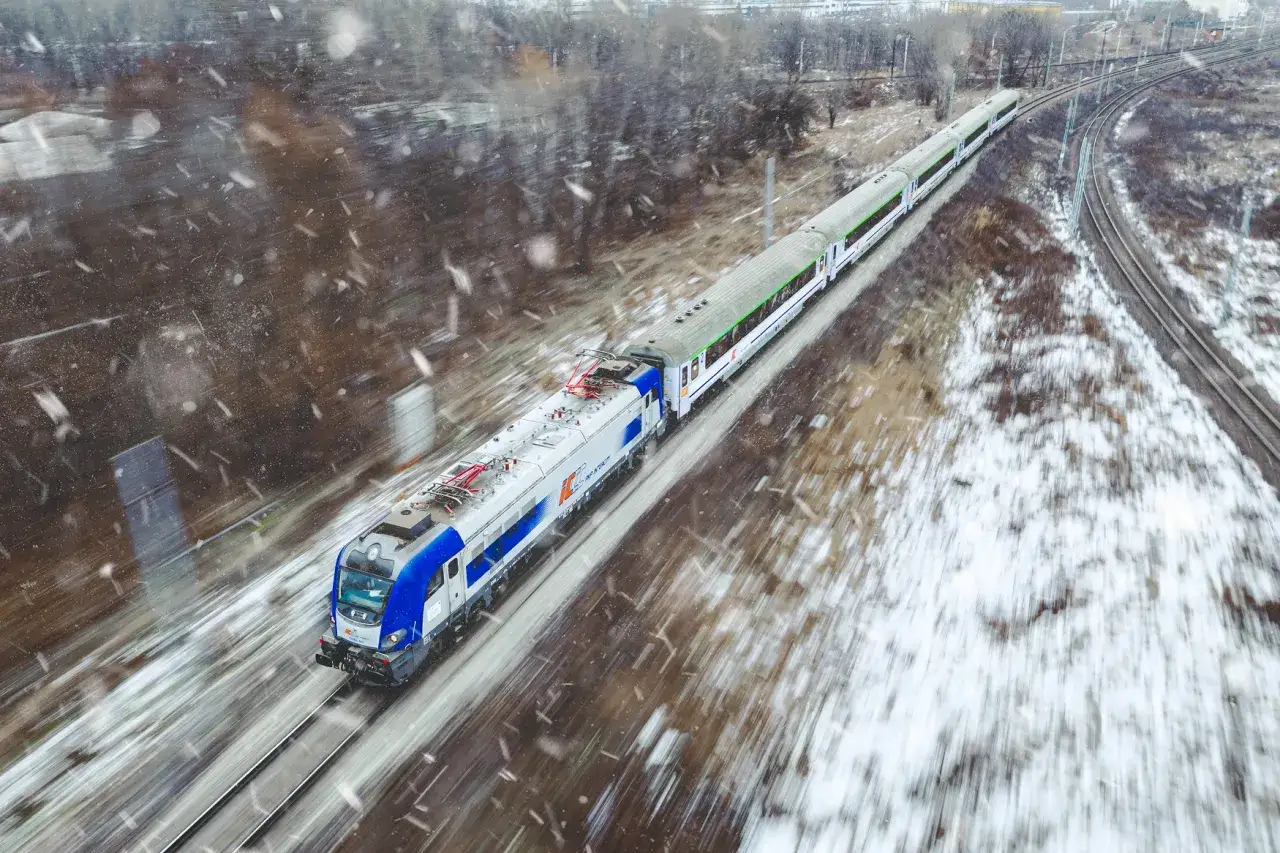 Pociąg PKP Intercity mknie przez zimowy krajobraz, łącząc Warszawę z Gdańskiem.