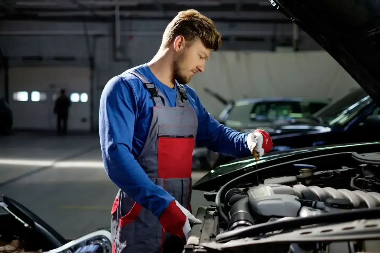 Mechanik sprawdza poziom oleju w silniku. Zastanawiasz się, ile zarabia elektronik samochodowy?