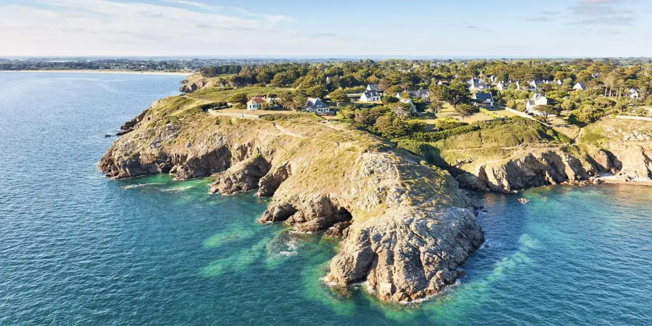 Vue aérienne de la presqu'île de Rhuys, avec ses falaises rocheuses plongeant dans une mer turquoise. Idéal pour une balade pittoresque.
