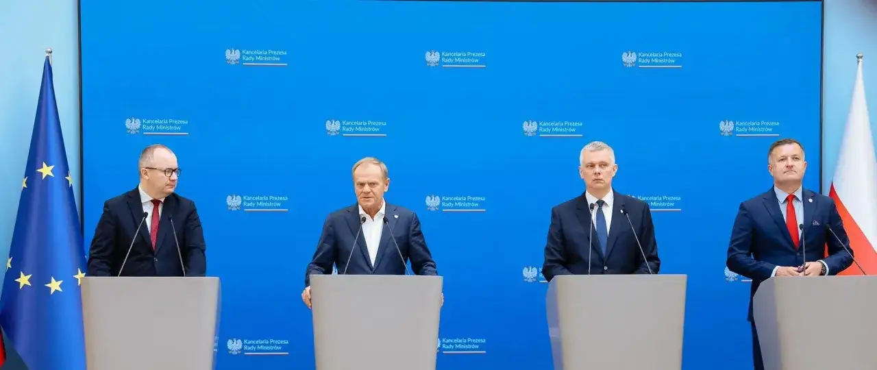 Czterech mężczyzn w garniturach stoi za mównicami. Dyskusja o ustawa lex tusk co to znaczy.