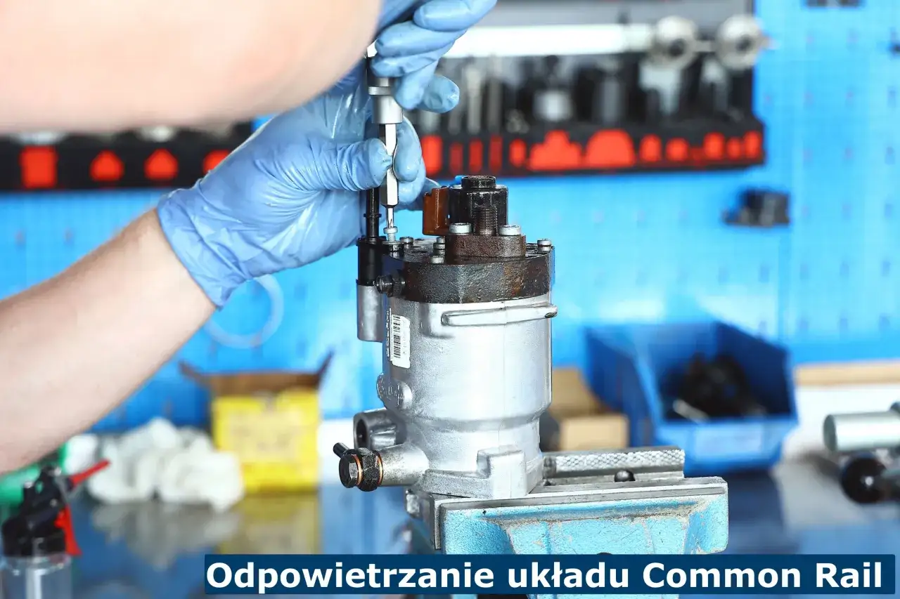 Mechanik w niebieskich rękawiczkach odpowietrza układ Common Rail, używając narzędzi do odpowietrzenia diesla po braku paliwa.