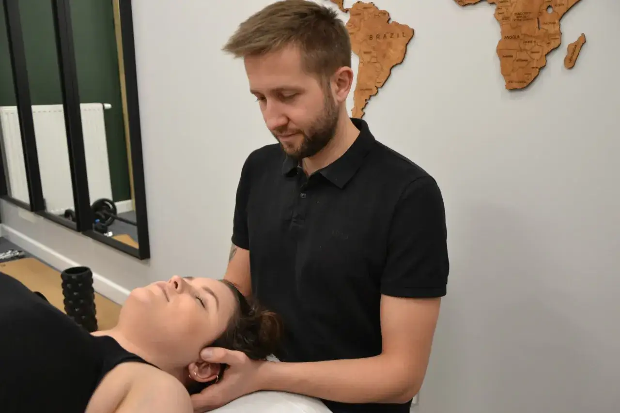Fizjoterapeuta wykonuje zabieg w ramach fizjoterapii stomatologicznej, delikatnie masując głowę pacjentki.