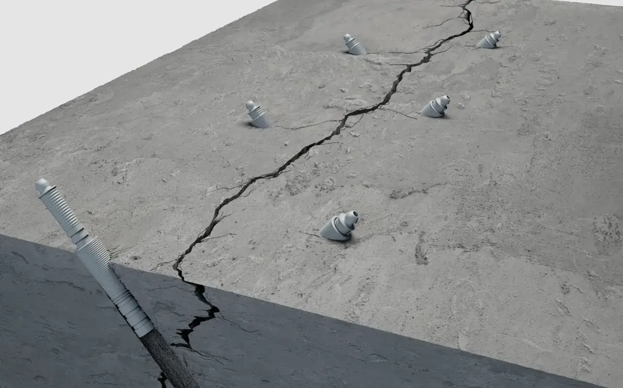 A cracked concrete surface with injection ports, illustrating how to fix concrete cracks.