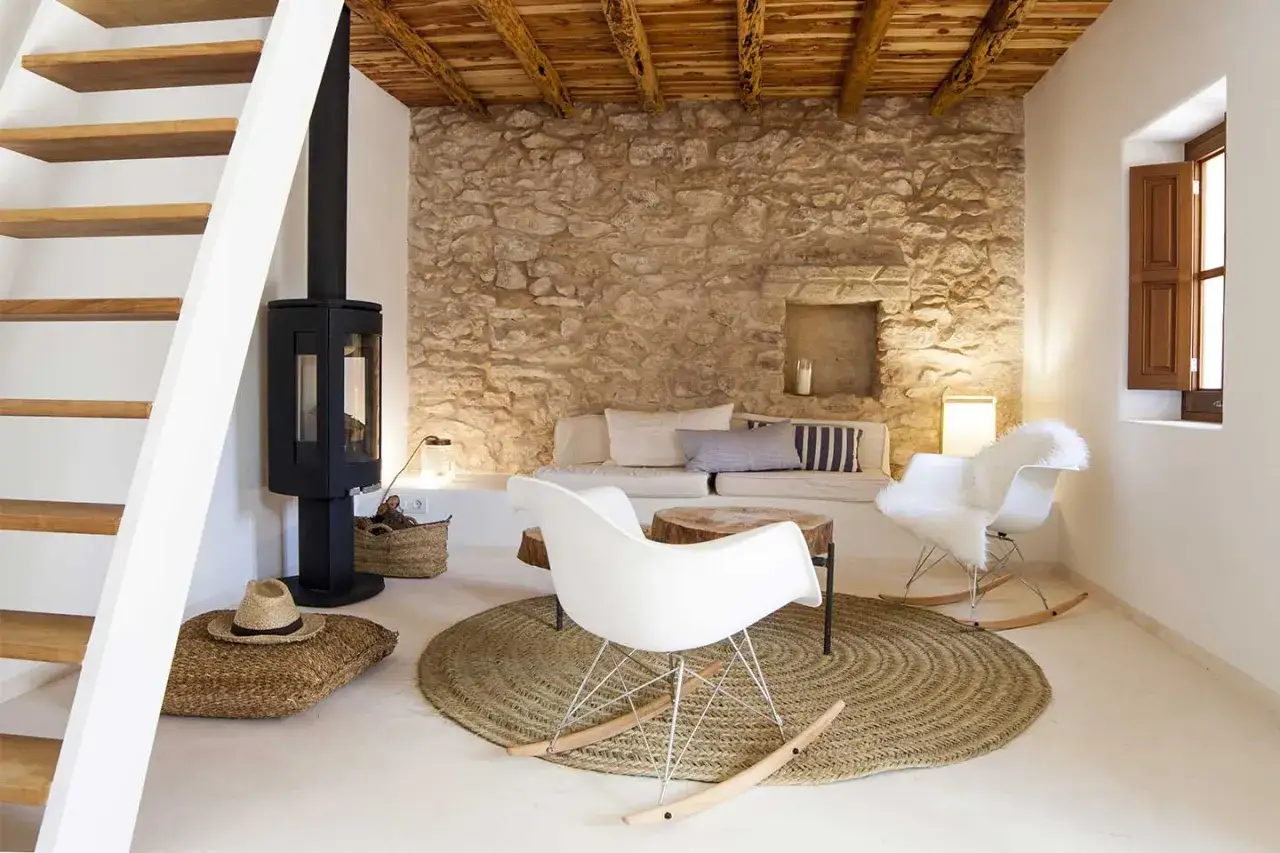 Accogliente soggiorno con camino, divano in pietra e sedie bianche. Un perfetto esempio di stile scandinavo casa, con travi a vista e materiali naturali.