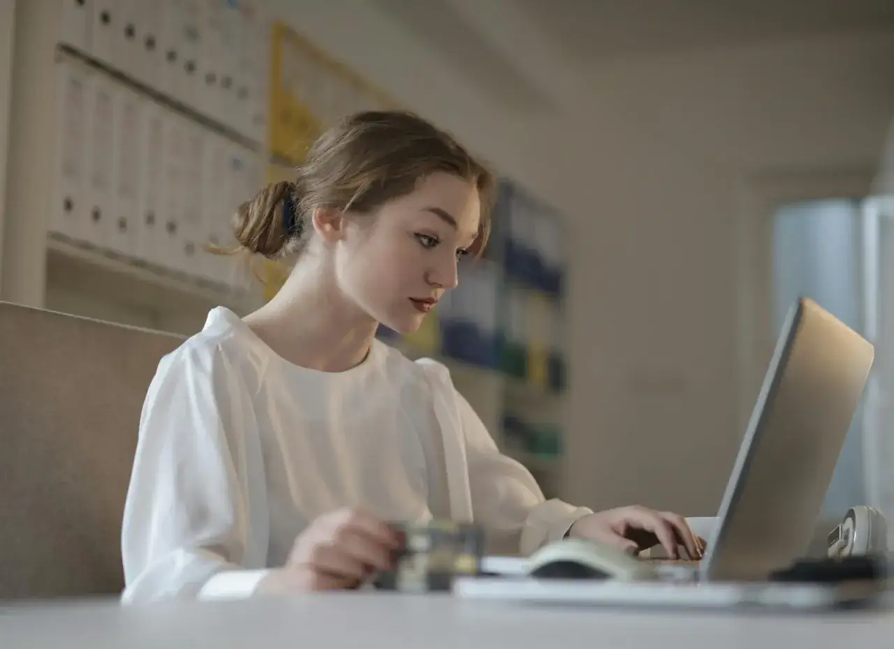 Młoda kobieta uczy się, jak zostać księgowym bez studiów, korzystając z laptopa i karty.
