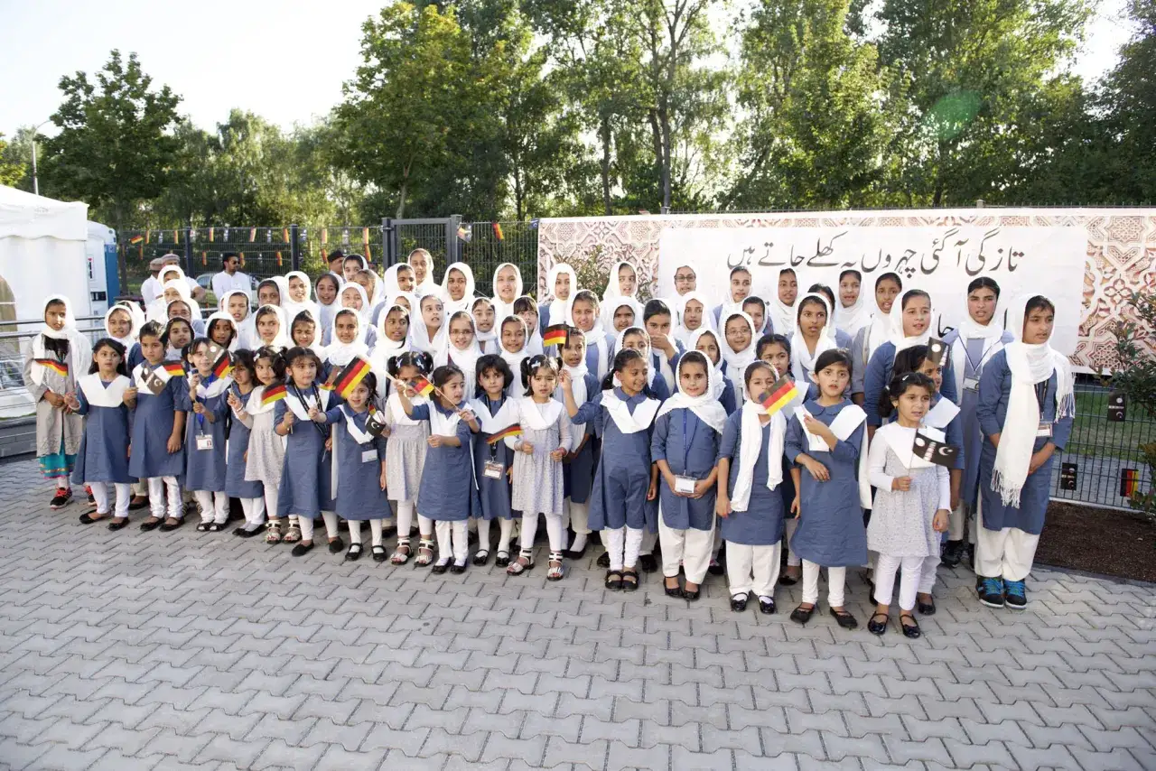 Kinder vor der Subhan Moschee halten deutsche und pakistanische Flaggen.