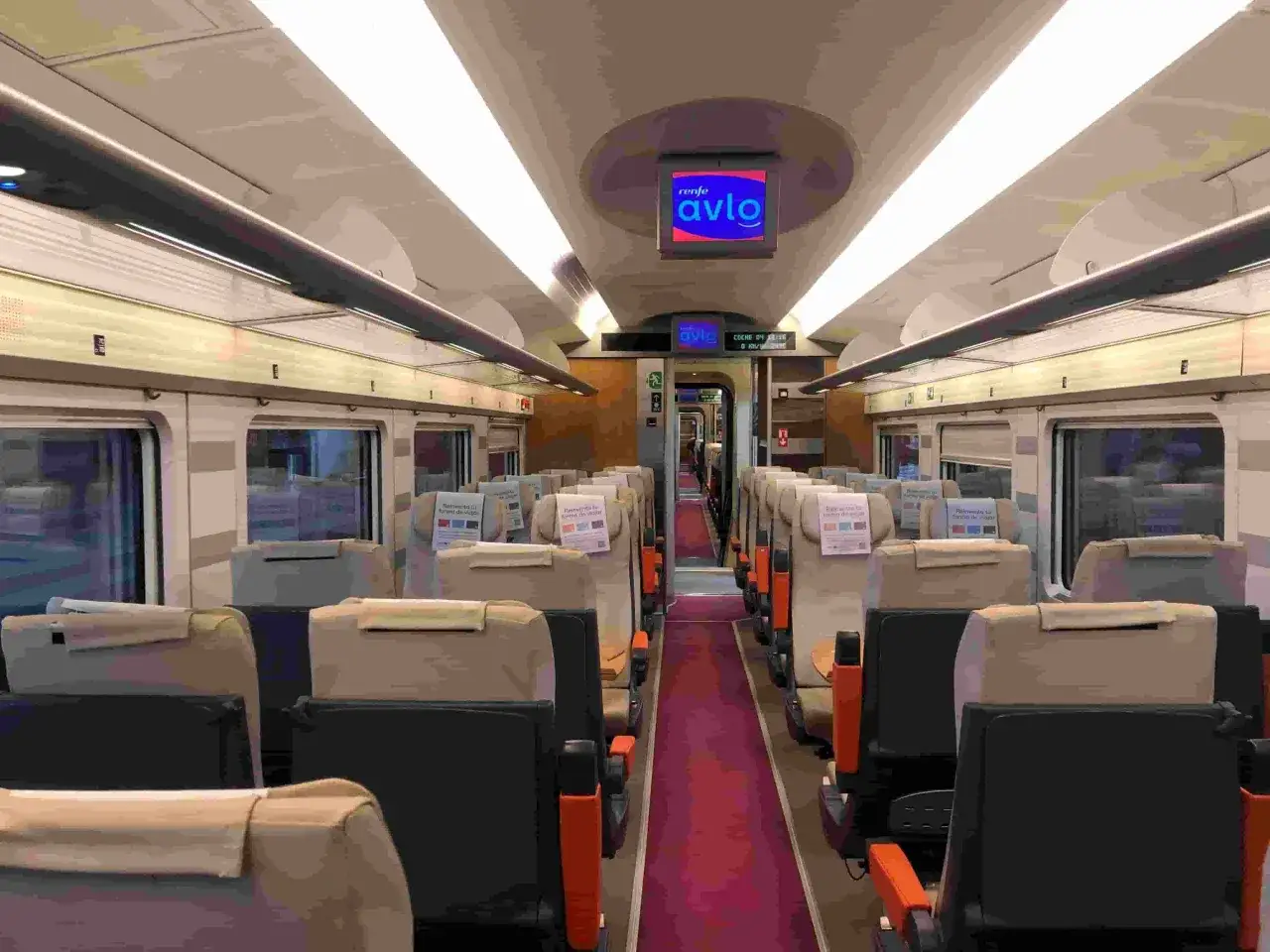 Interior de un tren Avlo, con asientos beige y pasillo rojo. Ideal para tu viaje Avlo Barcelona Madrid.