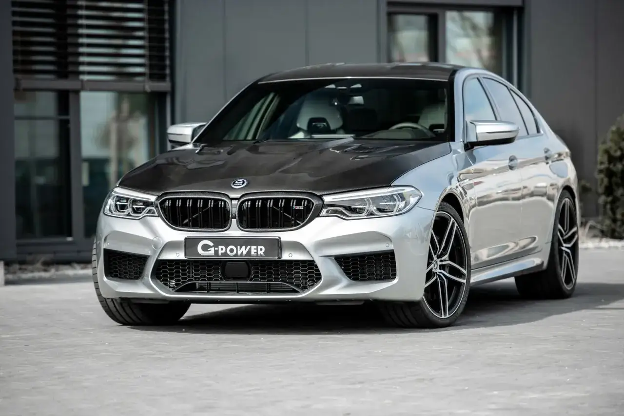 Srebrne BMW M5 G-Power z karbonową maską i agresywnym grillem, gotowe do podboju drogi.