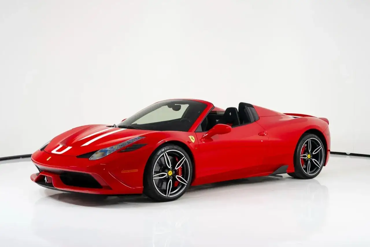 Czerwony kabriolet Ferrari 458 z białymi pasami na masce, gotowy do jazdy po torze.
