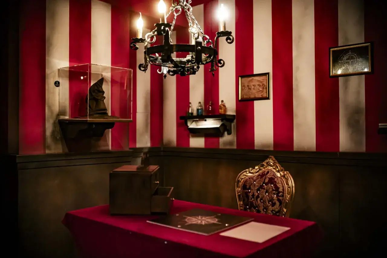Un cappello da stregone, ampolle e un antico scrittoio in una stanza a tema escape room dante.
