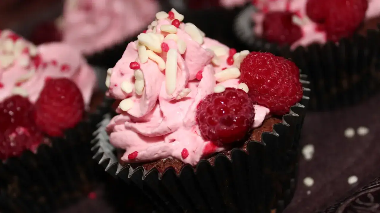 Kladdkakemuffins med rosa frosting, hallon och strössel. Perfekt för ett kladdkakemuffins recept!