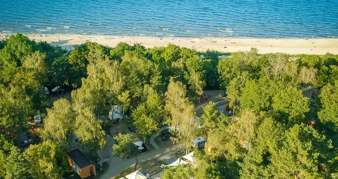 Idealny camping Trójmiasto: las, plaża i morze w zasięgu ręki. Widać namioty, kampery i domki.