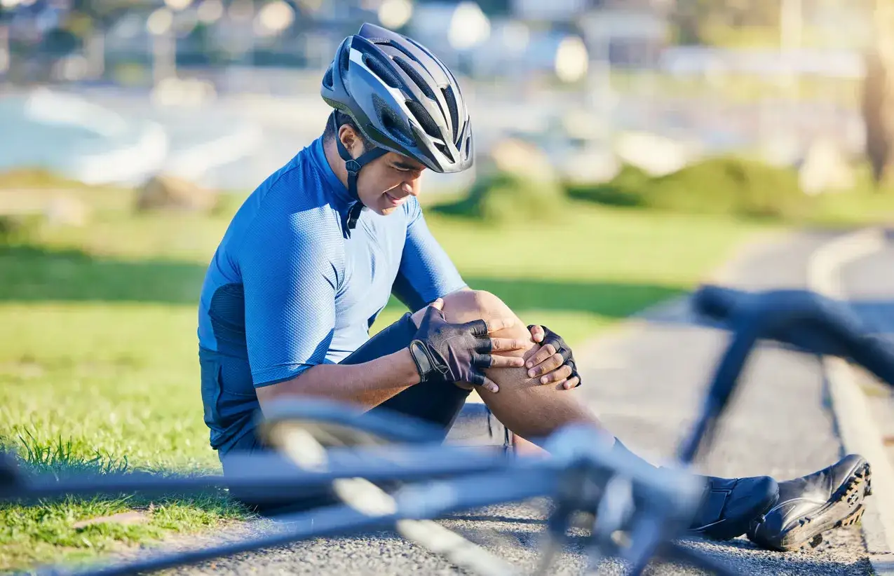 Cyclist holding his knee in pain, questioning if spinning is bad for your knees.